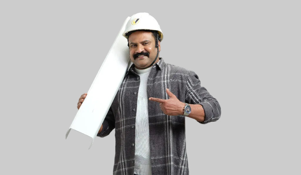 A man wearing a white hard hat, a gray and black plaid flannel shirt over a white turtleneck, and a watch, holding a long white metal channel against a dark gray background.
