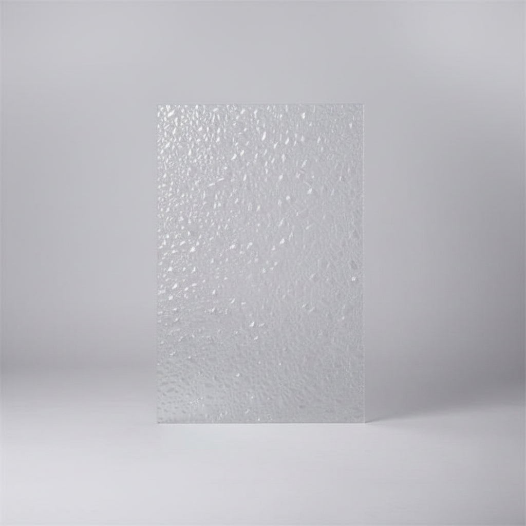 A textured clear polycarbonate sheet with a dense, reflective mosaic pattern, standing upright on a desk with an office background.