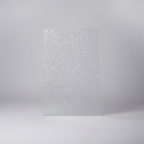 A textured clear polycarbonate sheet with a dense, reflective mosaic pattern, standing upright on a desk with an office background.