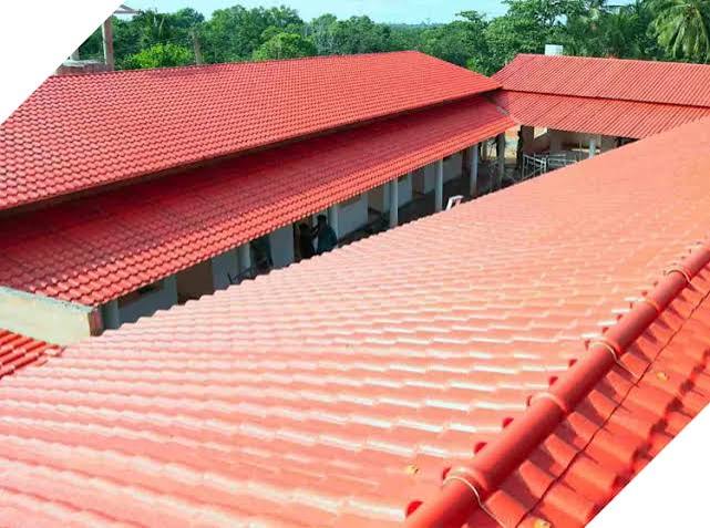Red clay tile roofs on buildings, shown from an elevated perspective with green trees in the background.