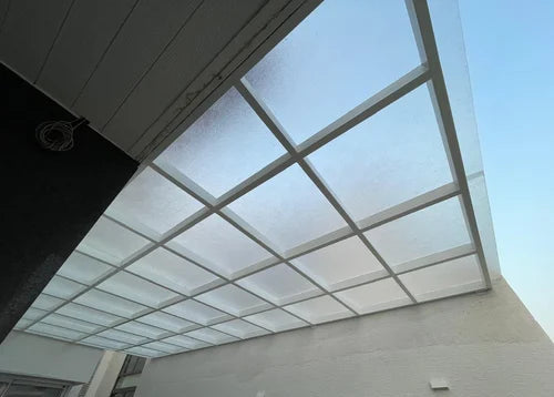 A modern translucent square skylight polycarbonate sheet with a white frame, installed on a patio ceiling under a clear blue sky.